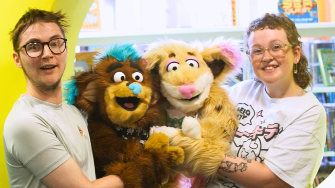 A photo of the cast of The OverTheres. From left to right - Basil puppeteer, Flint puppet, Cookie puppet, Rosie puppeteer